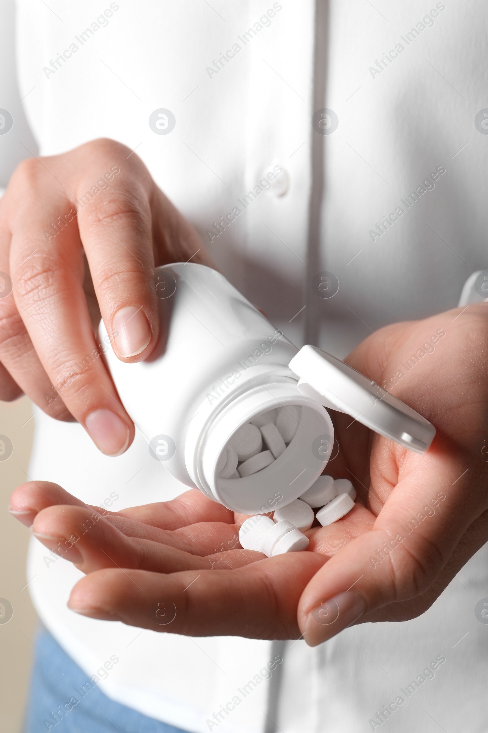 Photo of Woman pouring pills from bottle, closeup view