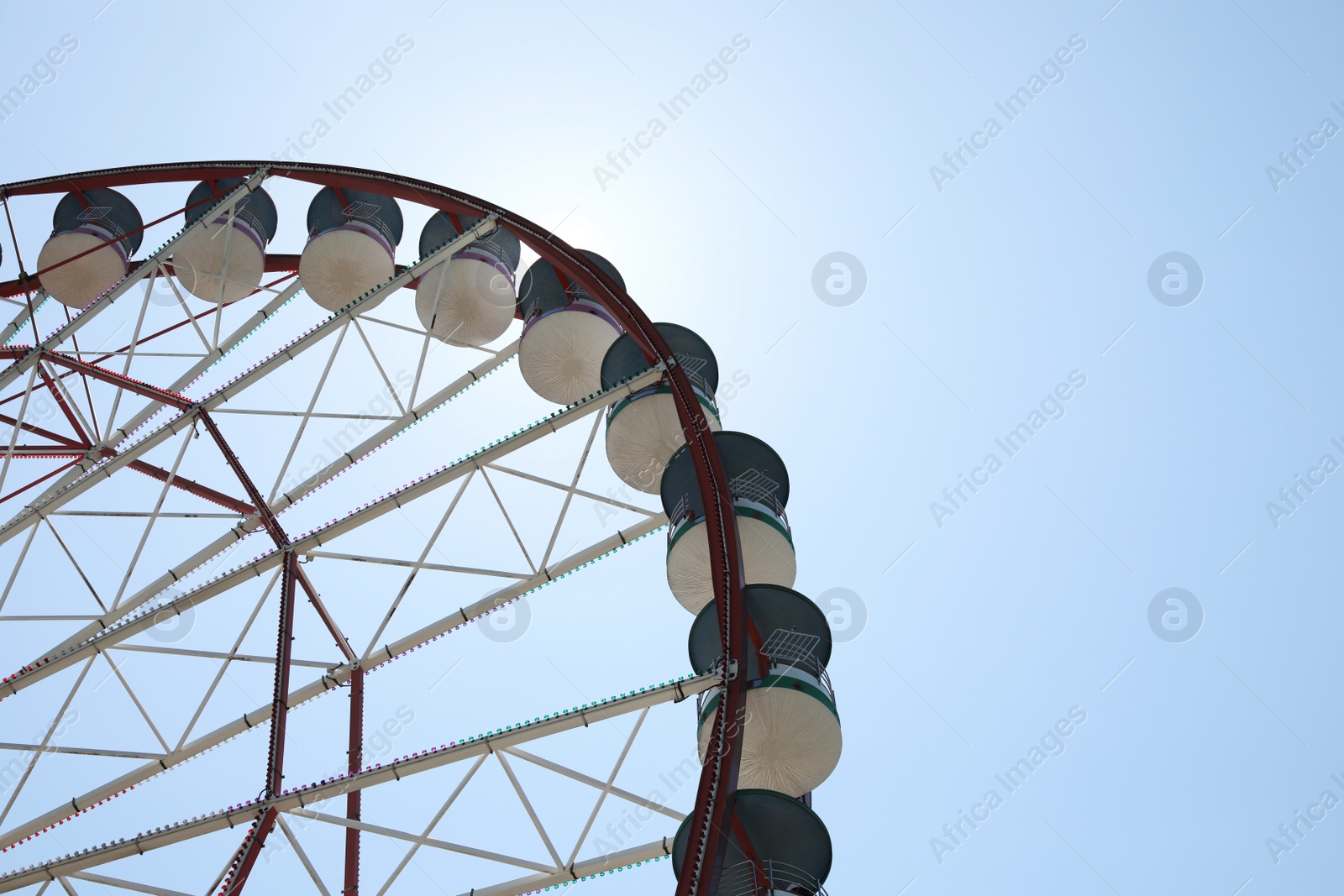 Photo of Beautiful Ferris wheel against blue sky on sunny day, low angle view