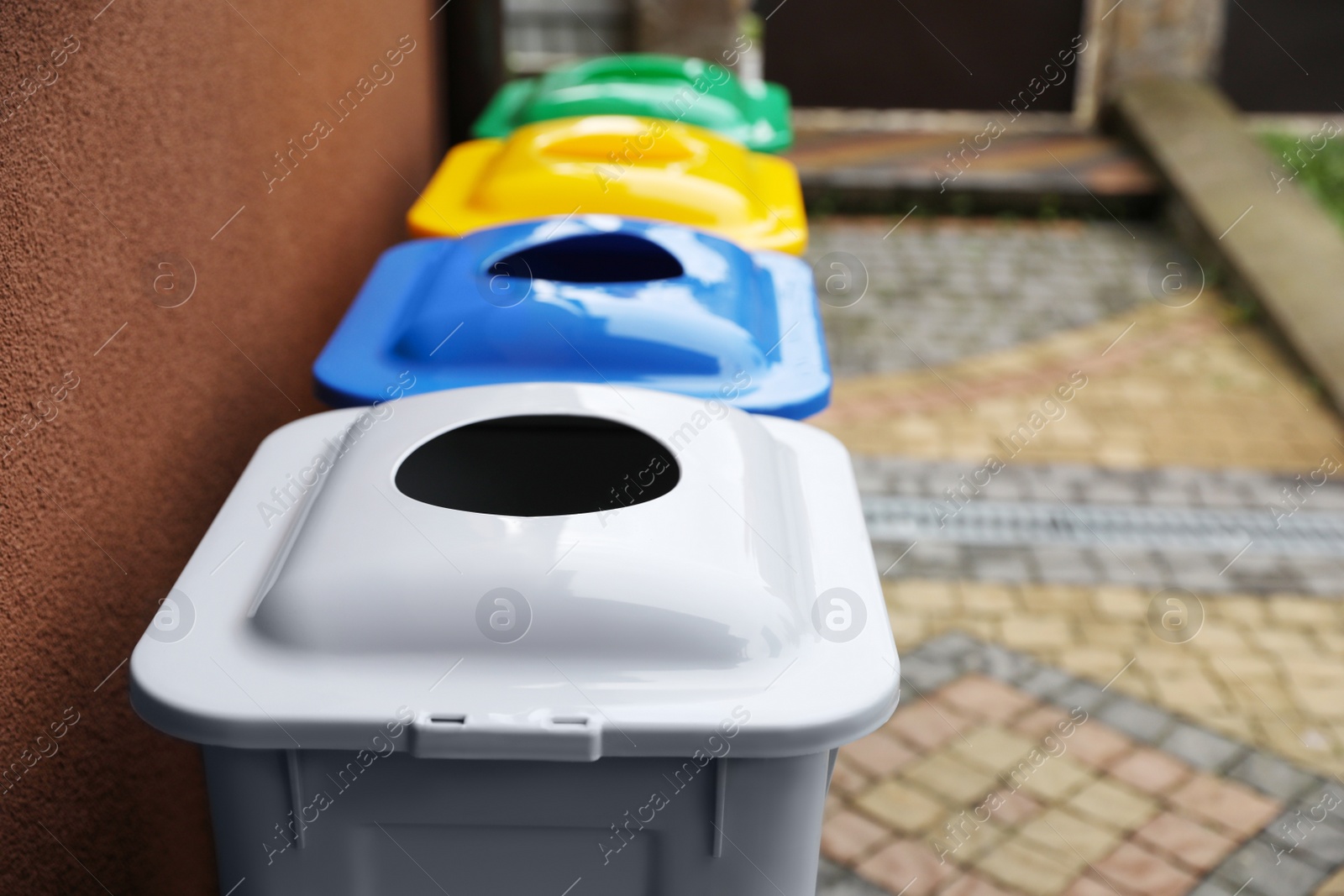 Photo of Many color recycling bins near brown wall outdoors, space for text