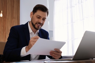 Photo of Businessman working with documents at table in office