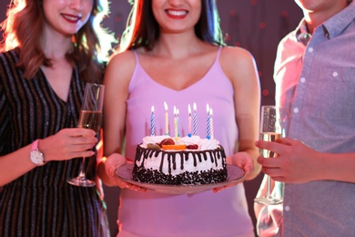 Young people with birthday cake in nightclub, closeup