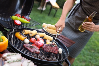 Photo of Man cooking on barbecue grill outdoors, closeup