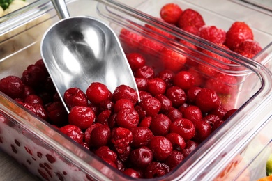 Photo of Box with frozen cherries and metal scoop, closeup