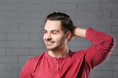 Portrait of young man with beautiful hair on brick wall background