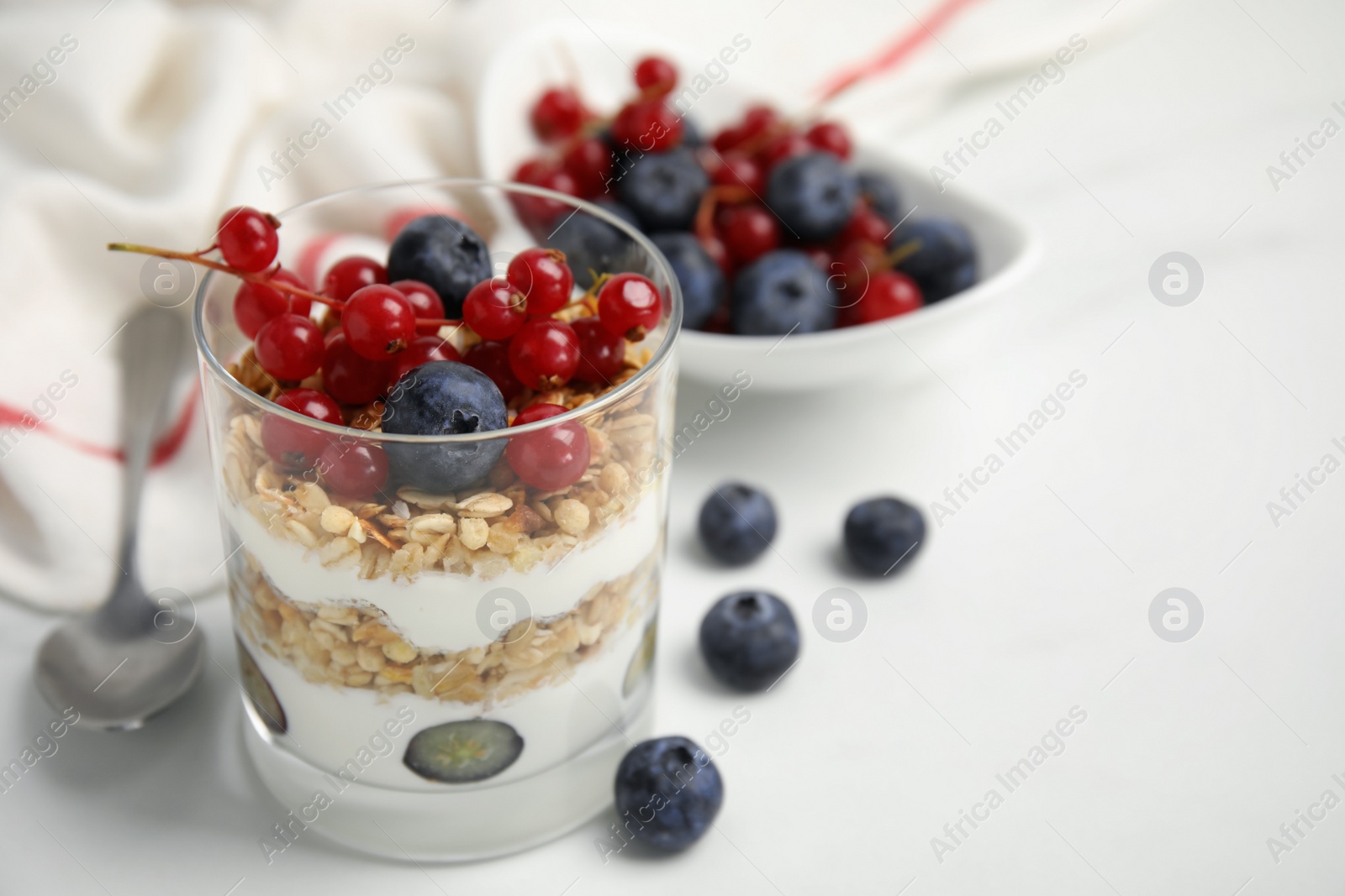 Photo of Delicious yogurt parfait with fresh berries on white table, closeup. Space for text