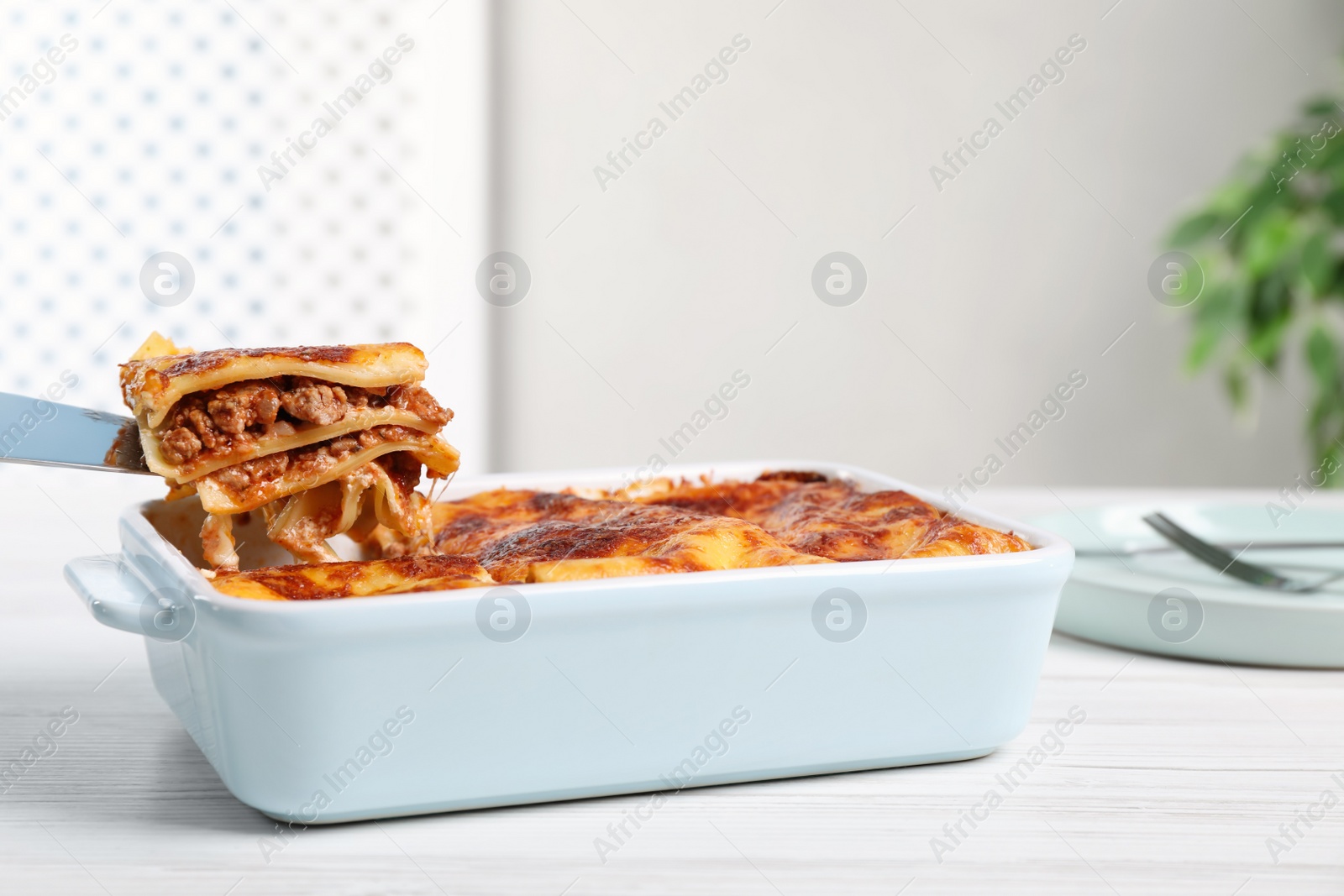 Photo of Tasty cooked lasagna in baking dish on white wooden table