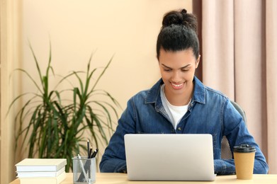 Photo of Smiling African American woman working on laptop at table indoors