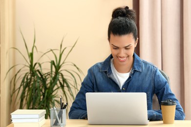 Smiling African American woman working on laptop at table indoors