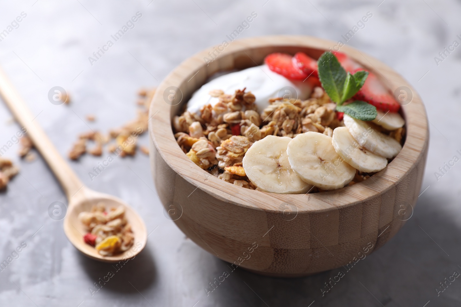 Photo of Tasty granola in bowl served on gray table, closeup