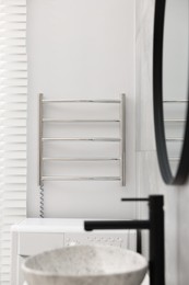 Photo of Modern heated towel rail on wall in bathroom