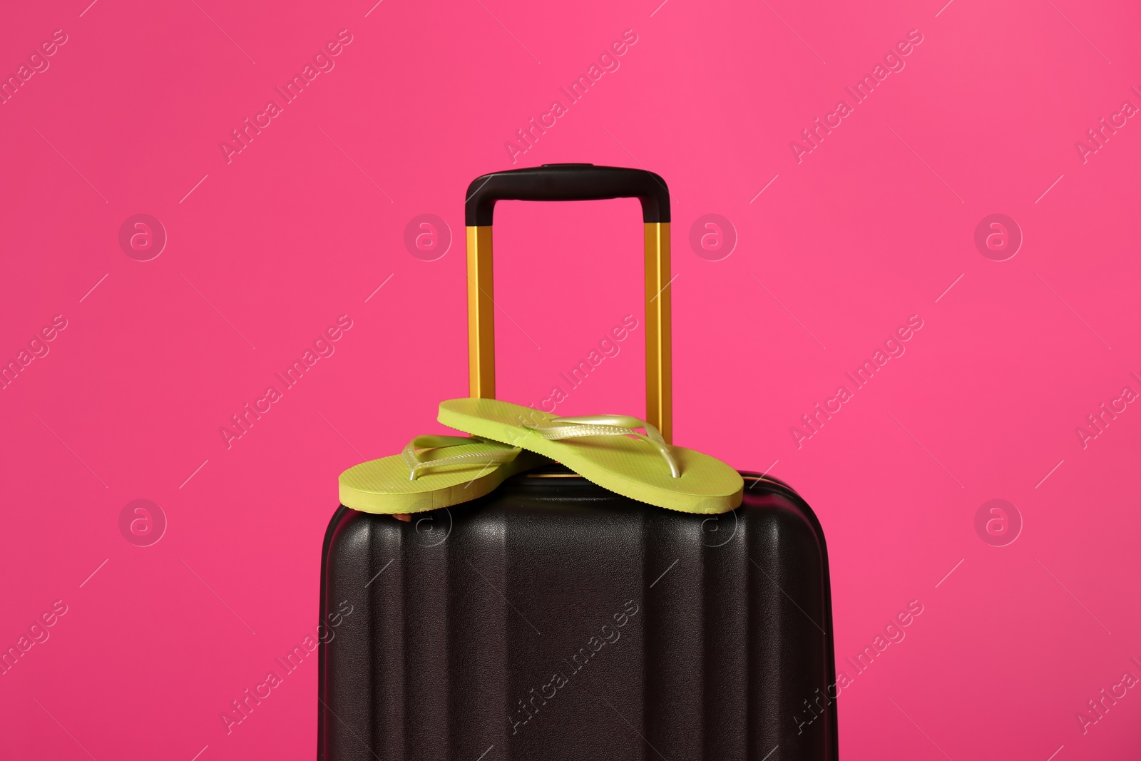 Photo of Stylish suitcase with flip flops on color background