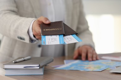 Travel agent with tickets and passports in office, closeup