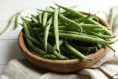 Photo of Fresh green beans in wooden bowl on table, closeup