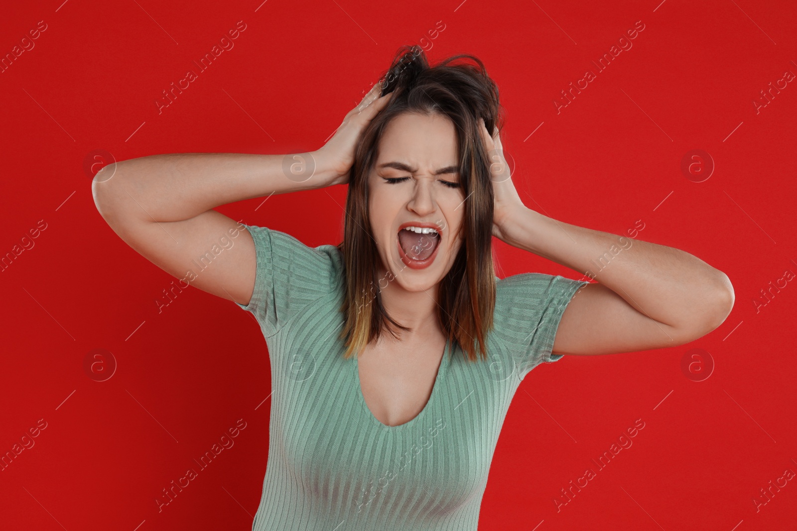 Photo of Beautiful young woman shouting on red background