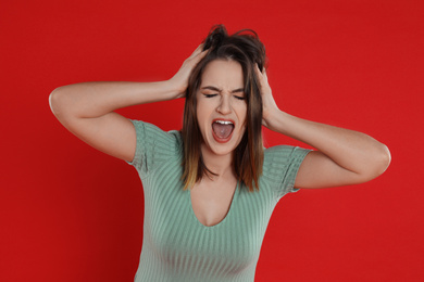 Beautiful young woman shouting on red background