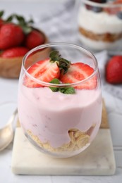 Photo of Glass with yogurt, strawberries and corn flakes on white textured table, closeup