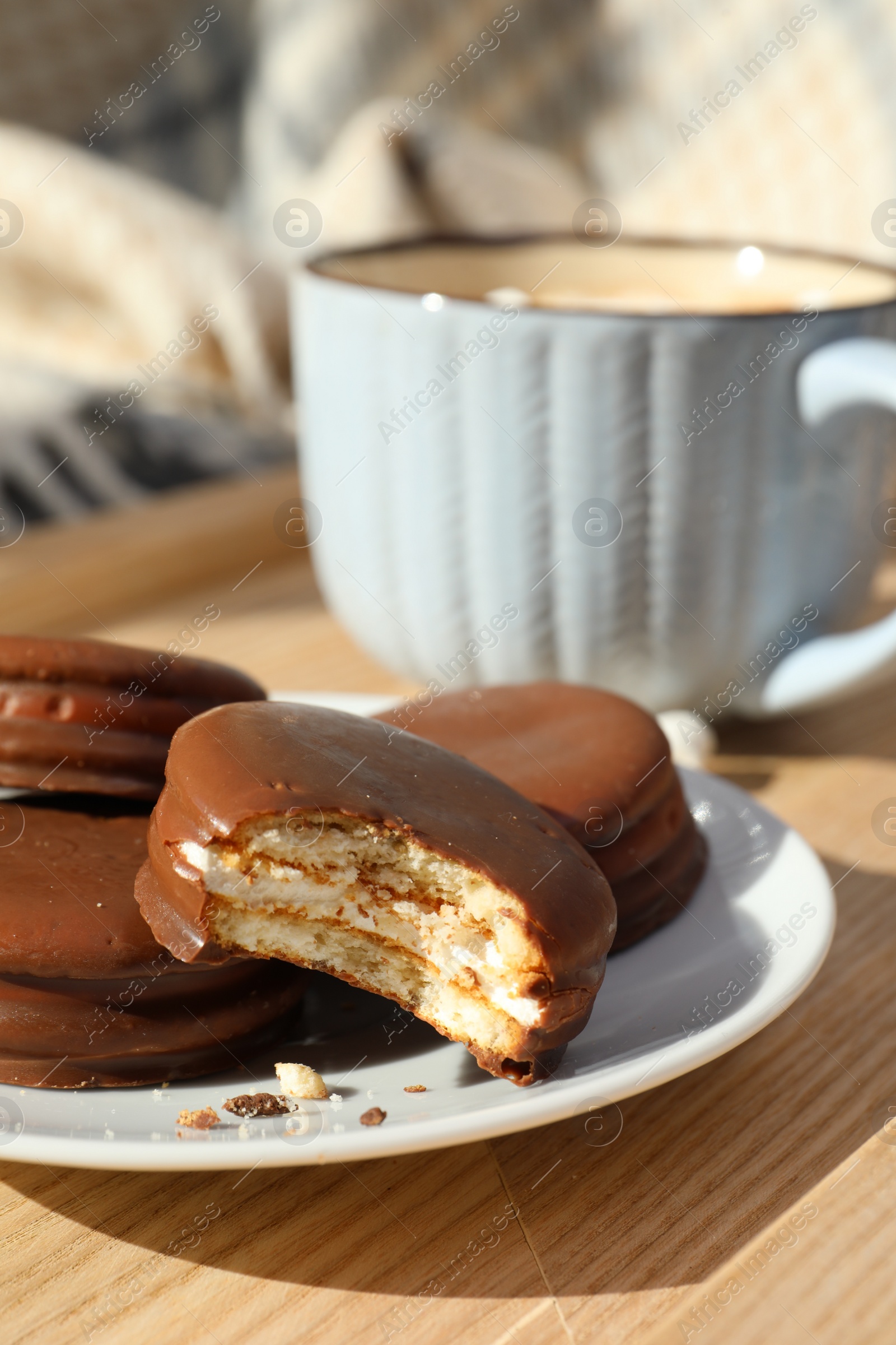 Photo of Tasty choco pies and cup of hot drink on wooden tray