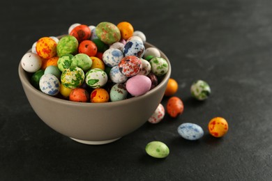 Photo of Ceramic bowl with delicious candies on dark grey table, closeup. Cooking utensil