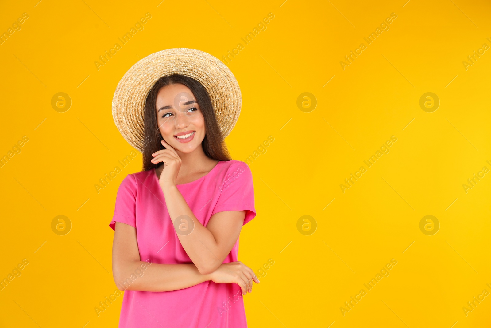 Photo of Young woman wearing stylish pink dress on yellow background. Space for text