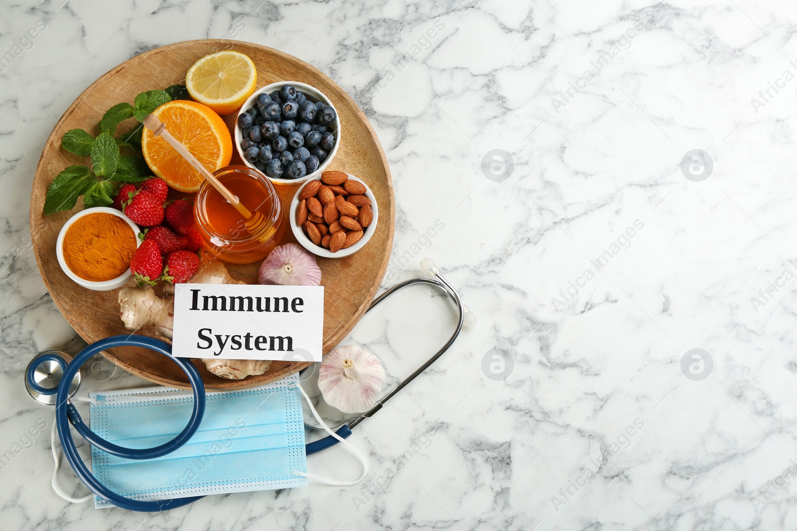 Photo of Card with phrase Immune System, medical items and fresh products on light marble table, flat lay. Space for text