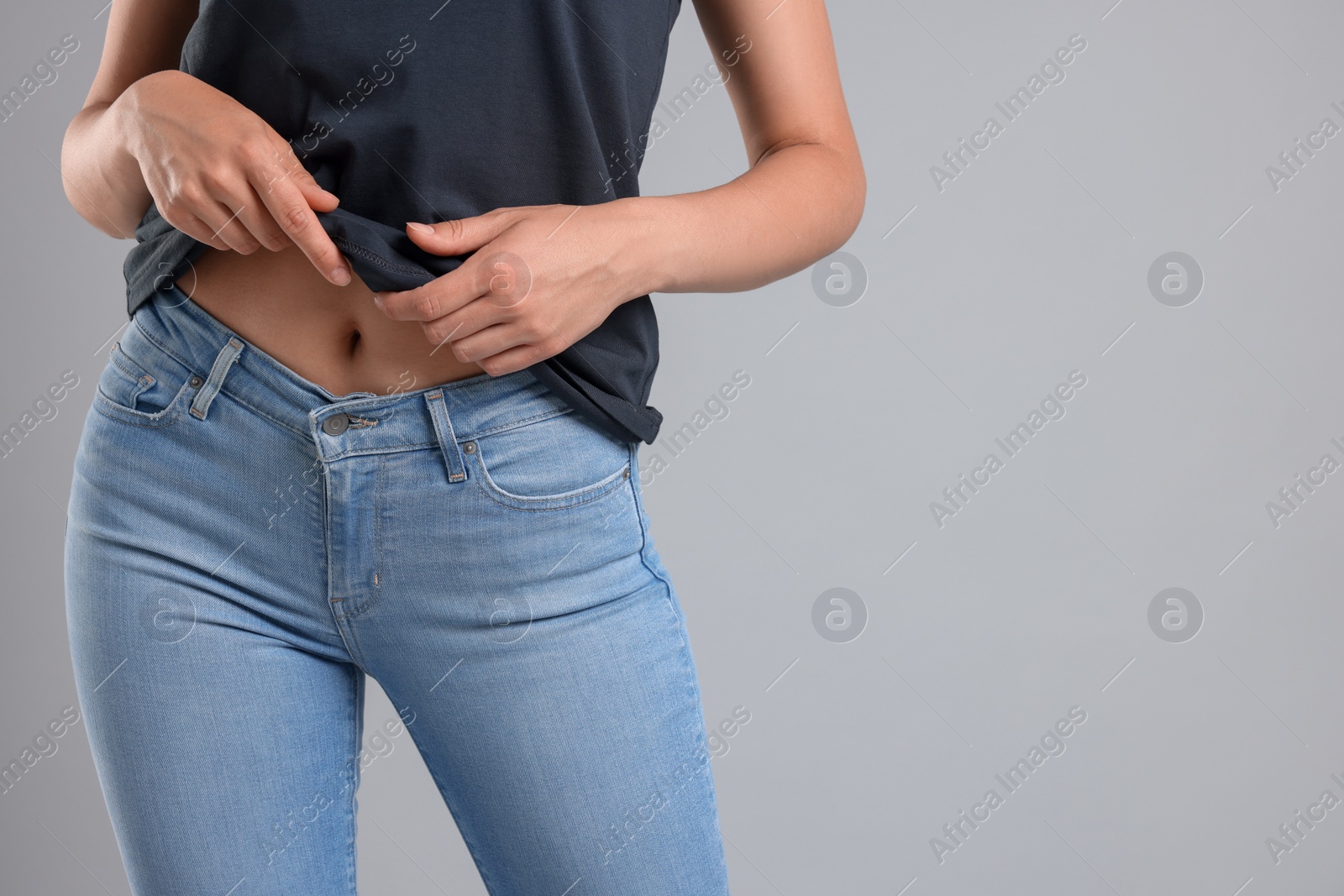 Photo of Woman wearing stylish jeans on light gray background, closeup. Space for text