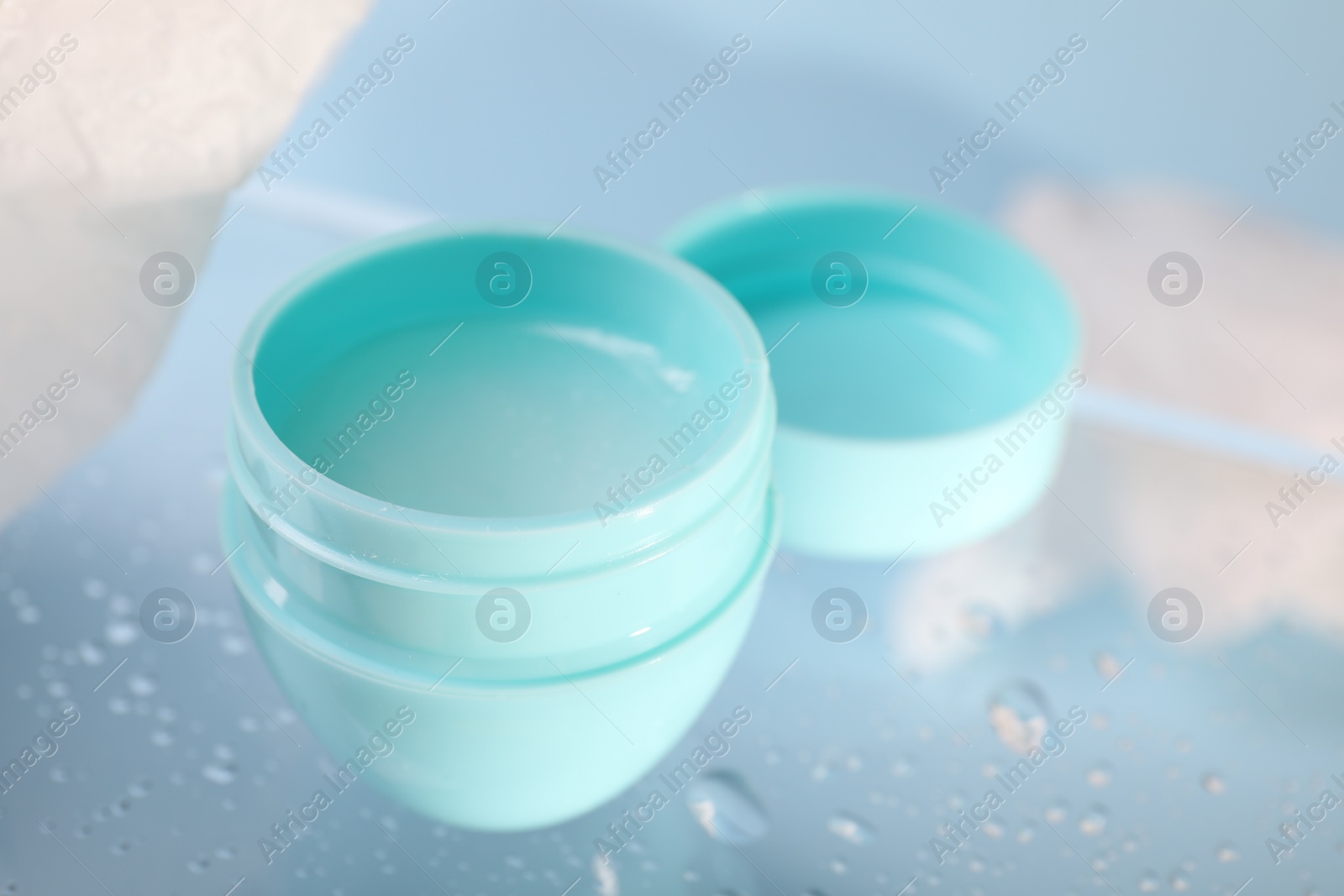 Photo of Lip balm and water drops on glass surface, closeup