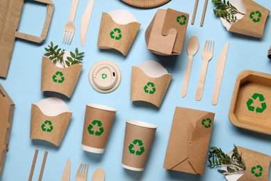 Image of Set of eco friendly food packaging with recycling symbols on light blue background, flat lay