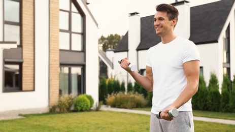 Photo of Sporty man doing exercise with dumbbells on backyard. Healthy lifestyle