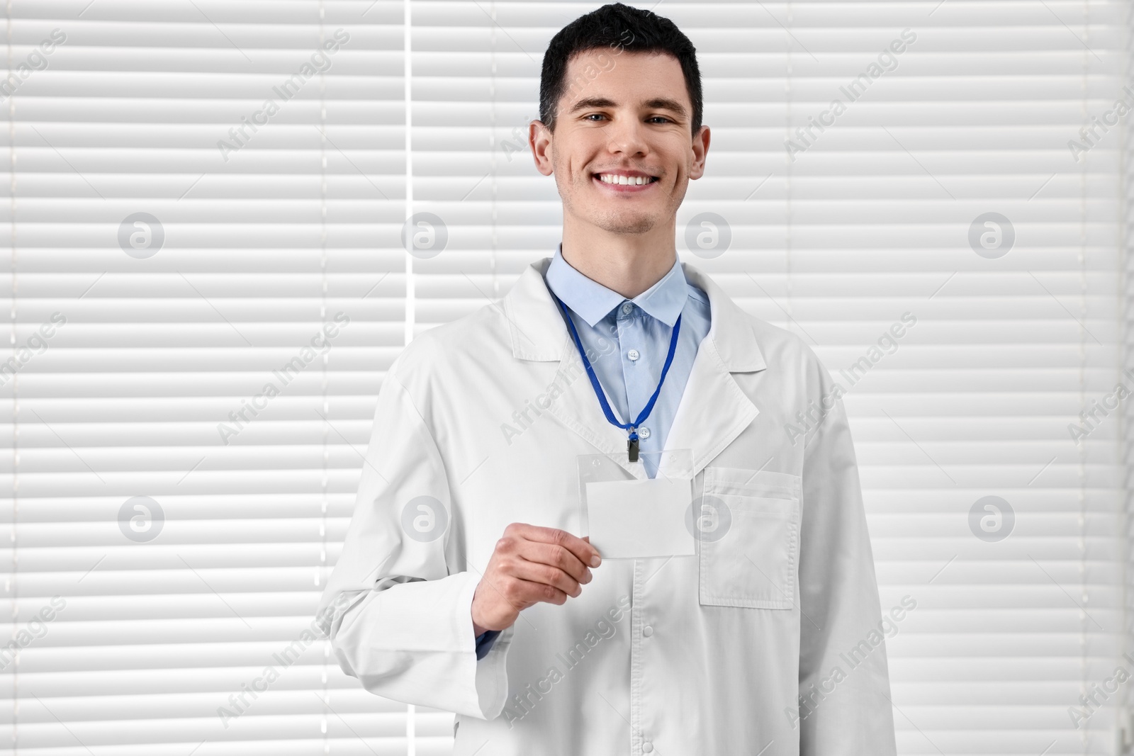 Photo of Smiling doctor showing empty badge in hospital