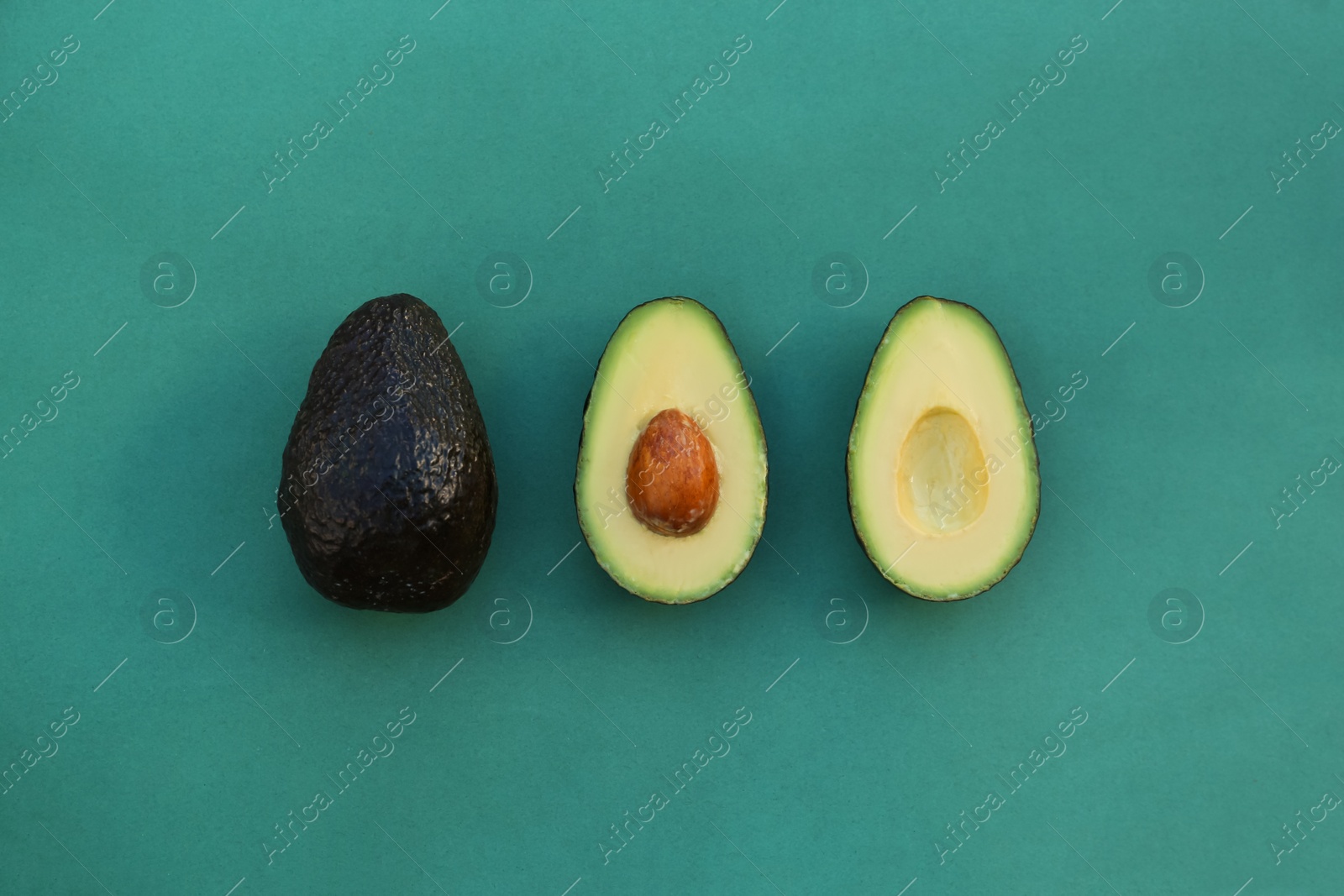 Photo of Tasty fresh avocados on dark turquoise background, flat lay