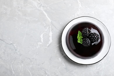 Delicious jelly with blackberries and mint on grey table, top view. Space for text