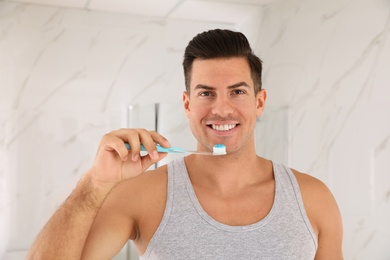 Photo of Man holding toothbrush with paste at home