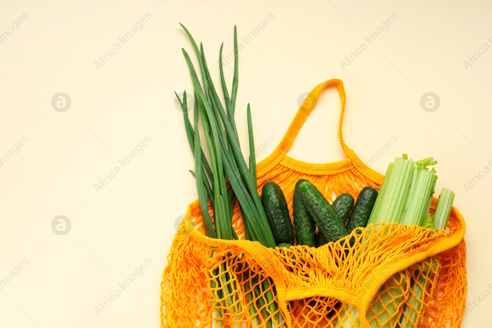 Photo of String bag with different vegetables on beige background, top view. Space for text