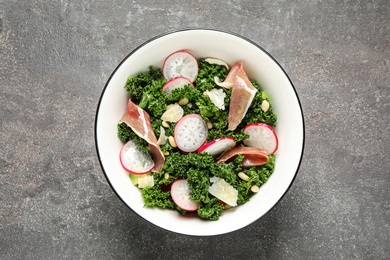 Tasty fresh kale salad on grey table, top view