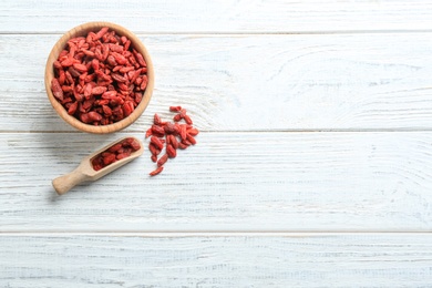 Photo of Flat lay composition with dried goji berries on white wooden table, space for text. Healthy superfood