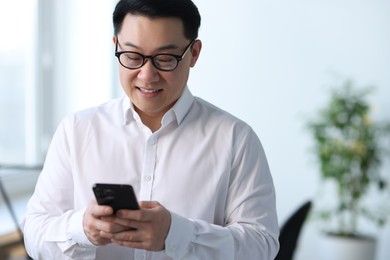 Photo of Portrait of smiling businessman with smartphone in office