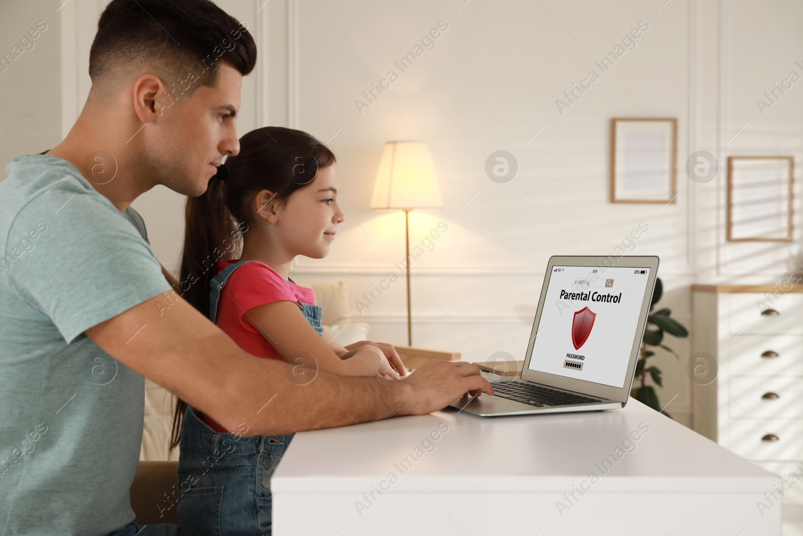 Photo of Father installing parental control app on laptop to ensure his child's safety at home