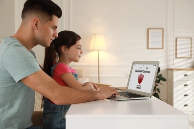 Photo of Father installing parental control app on laptop to ensure his child's safety at home