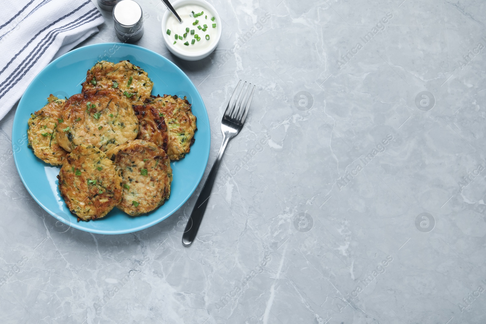 Photo of Delicious zucchini pancakes served on grey table, flat lay. Space for text