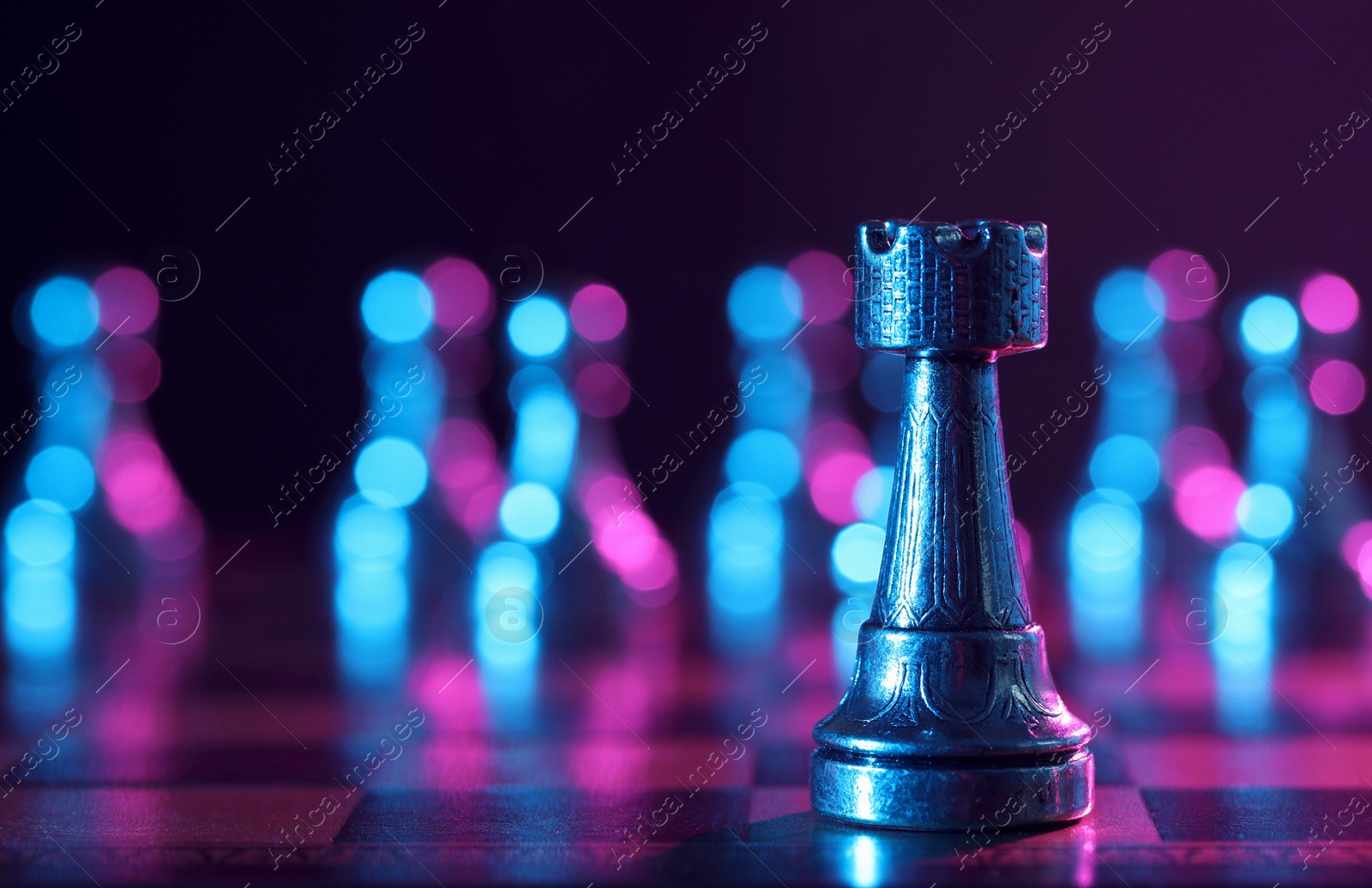 Photo of Rook on chessboard in color light, selective focus. Space for text