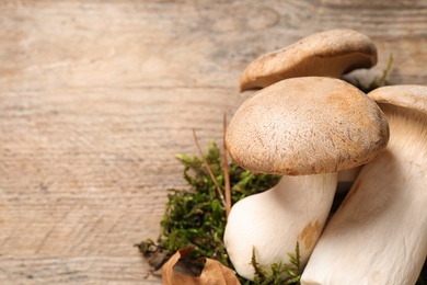 Photo of Fresh wild mushrooms on wooden table, closeup view. Space for text