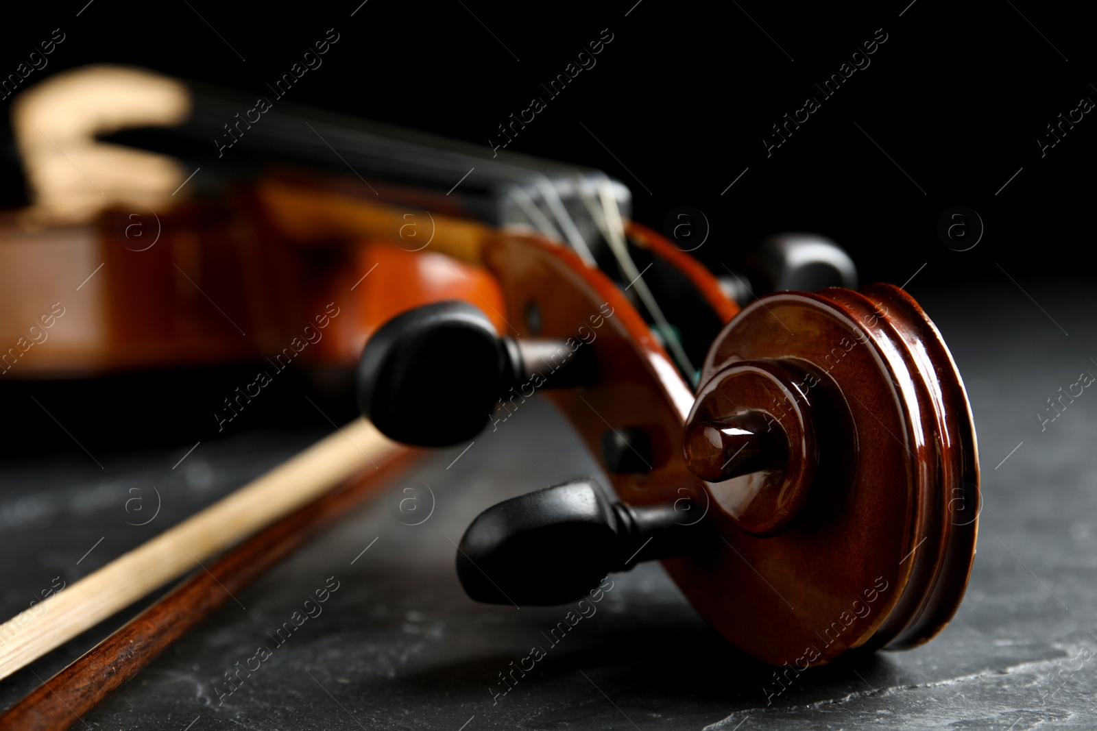 Photo of Classic violin and bow on grey stone table, closeup