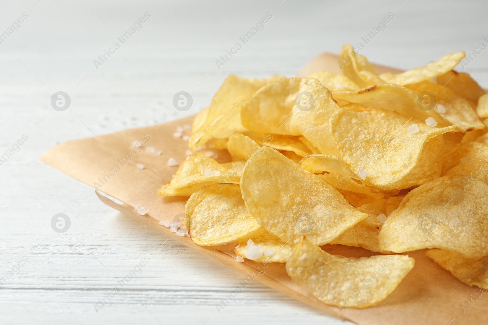 Photo of Delicious crispy potato chips on table, closeup with space for text