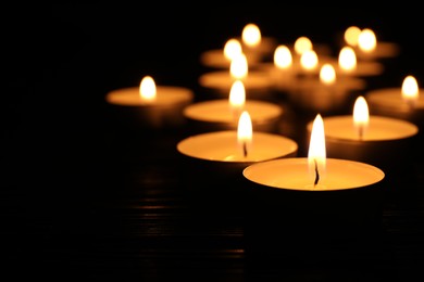 Photo of Burning candles and space for text on black background, closeup. Memory day