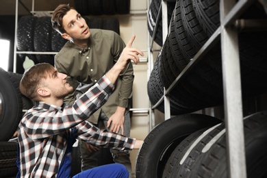 Service center consultant helping customer to choose tire in store