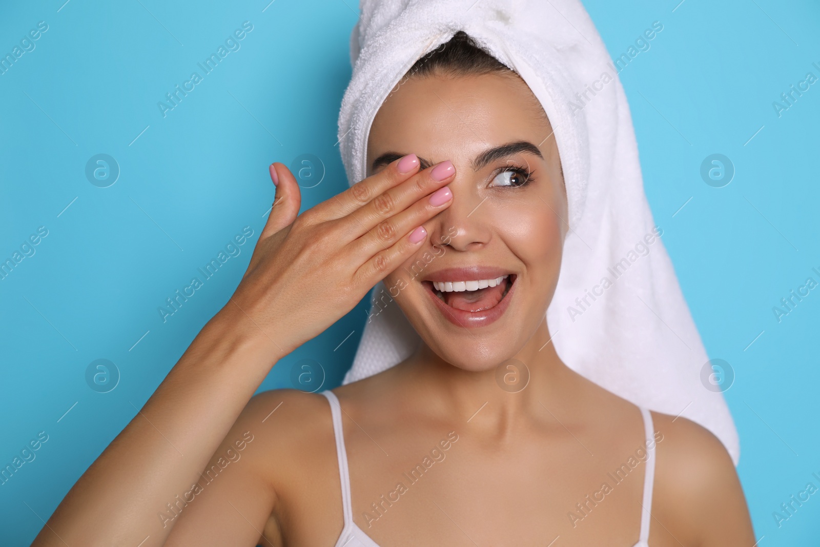 Photo of Beautiful young woman with towel on head against light blue background