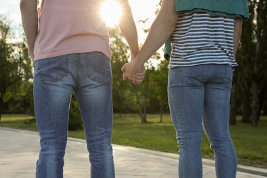 Photo of Gay couple holding hands together in park on sunny day, back view