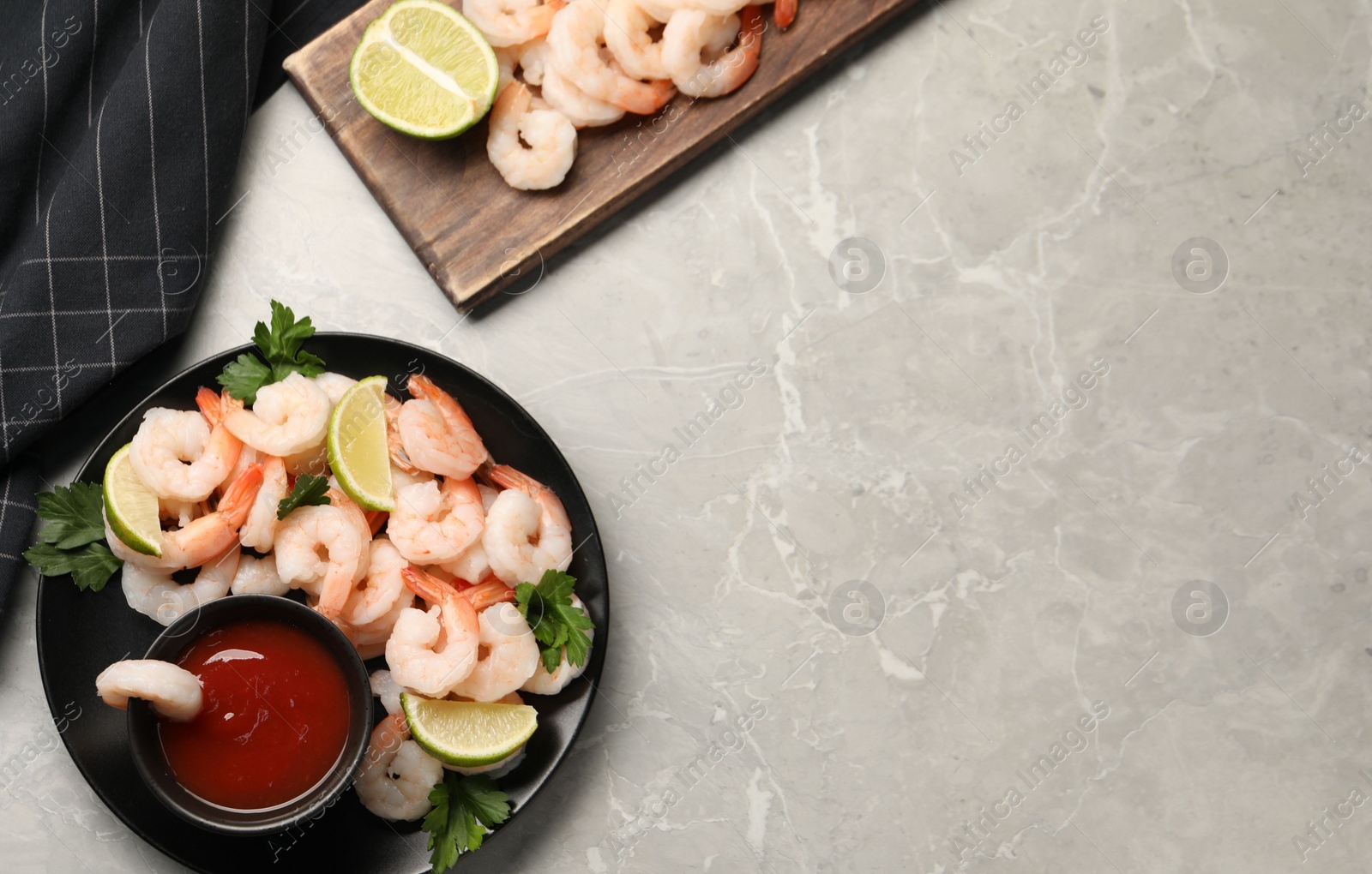 Photo of Tasty boiled shrimps with cocktail sauce, parsley and lime on light grey table, flat lay. Space for text