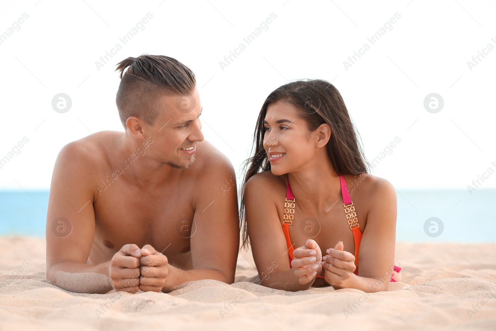 Photo of Young woman in bikini spending time with her boyfriend on beach. Lovely couple