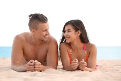 Young woman in bikini spending time with her boyfriend on beach. Lovely couple